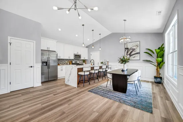 an open kitchen with wooden floor and stainless steel appliances