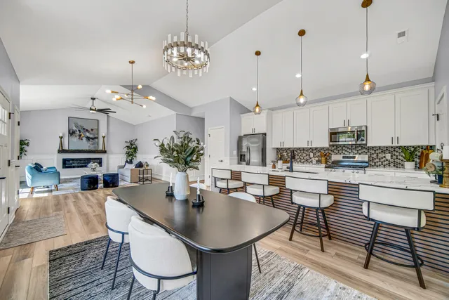 a kitchen with kitchen island a dining table chairs and white cabinets