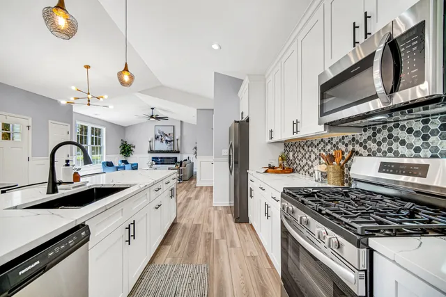 a kitchen with stainless steel appliances granite countertop a stove a sink dishwasher and a microwave oven with white cabinets