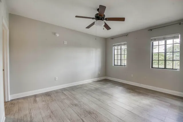 an empty room with windows and ceiling fan