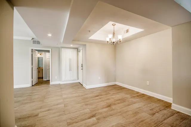 an empty room with wooden floor closet and chandelier fan