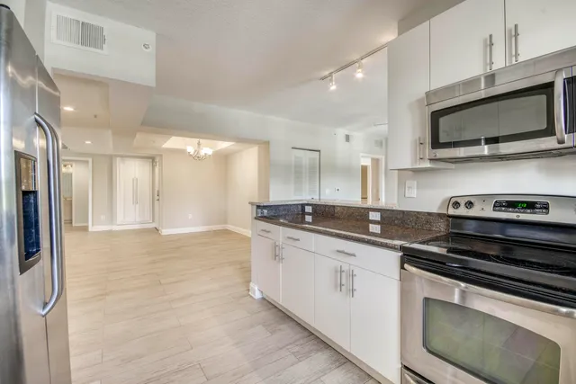 an empty room with wooden floor chandelier fan and windows