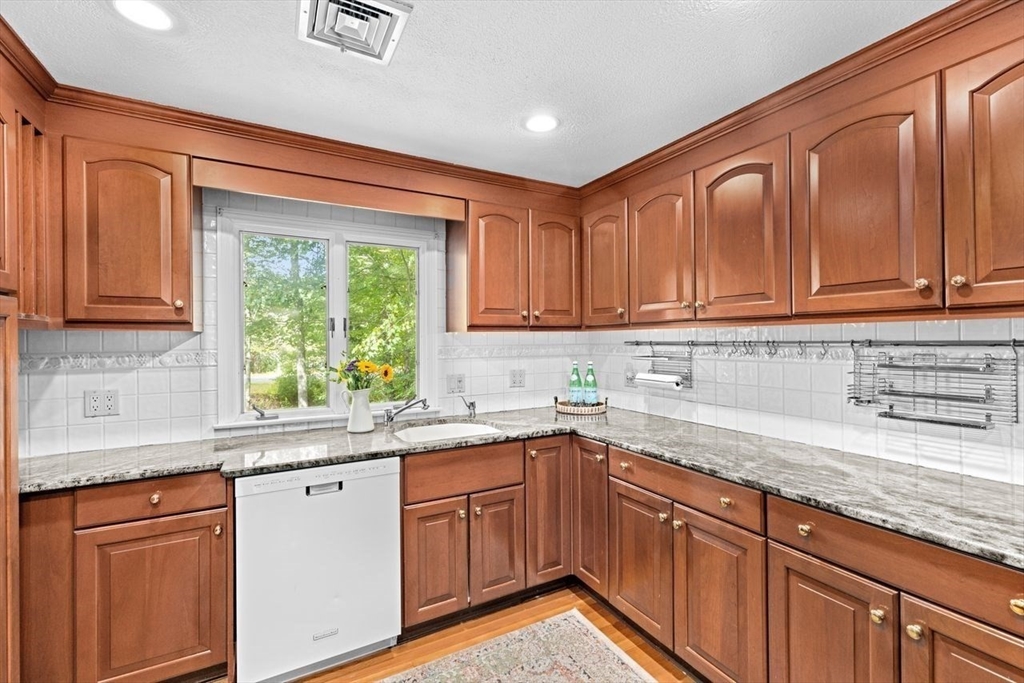 131 Cross Street Norwell, MA 02061 - Photo 7 of 41 a kitchen with stainless steel appliances granite countertop a sink dishwasher cabinets and granite countertops with wooden floor