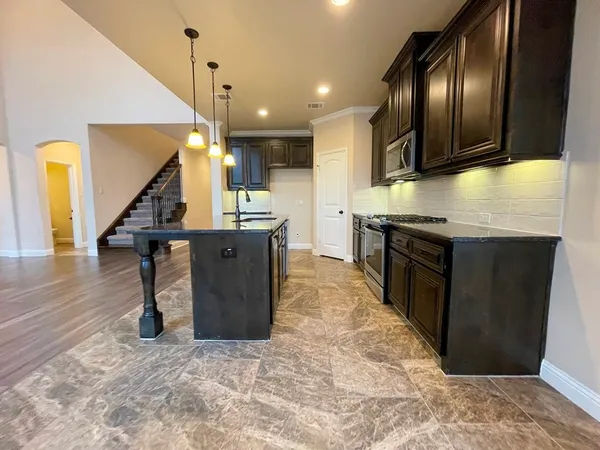 a kitchen with stainless steel appliances granite countertop a refrigerator a stove and a sink