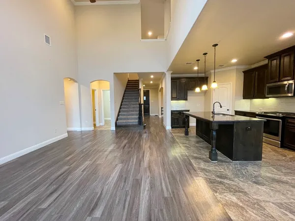 a kitchen with stainless steel appliances kitchen island granite countertop a refrigerator a stove and a wooden floors