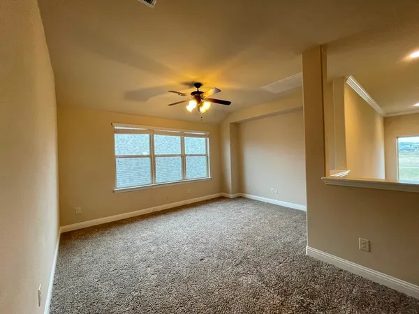 an empty room with windows and chandelier fan