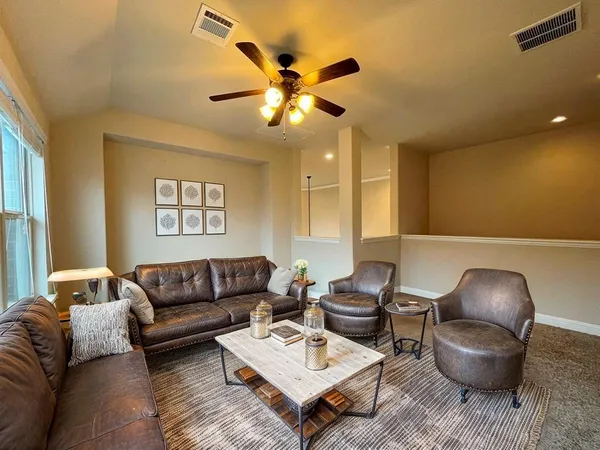 a living room with furniture and a ceiling fan