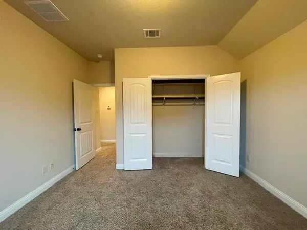 a bedroom with a large bed and a flat tv screen on dresser