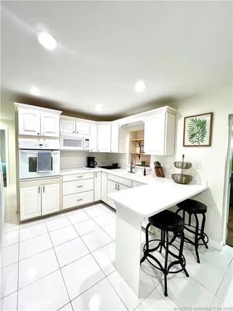 a kitchen with stainless steel appliances a stove a sink and white cabinets with wooden floor