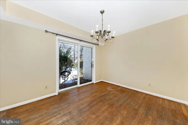 an empty room with wooden floor chandelier and windows