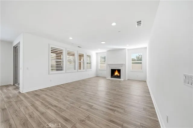 a large white kitchen with kitchen island a sink dishwasher a refrigerator and white cabinets with wooden floor