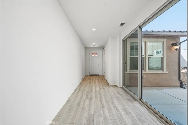 an empty room with wooden floor a ceiling fan white walls and windows