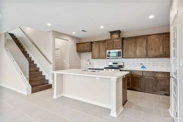 a kitchen with stainless steel appliances granite countertop a stove top oven a sink and dishwasher a oven with wooden cabinets