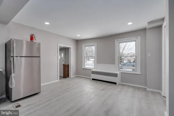 a view of an empty room with window and refrigerator
