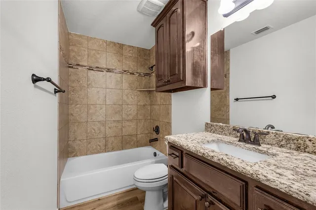 a bathroom with a granite countertop toilet sink and mirror