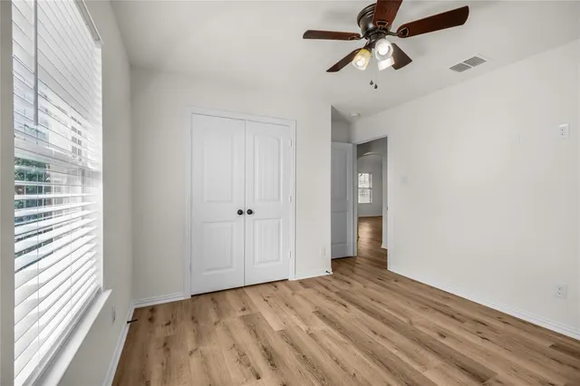 a view of empty room with wooden floor and fan