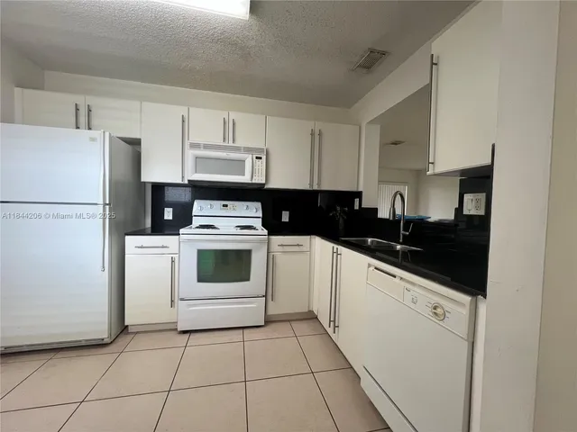 a white kitchen with a stove a refrigerator and cabinets