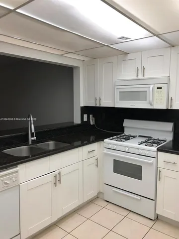 a kitchen with granite countertop white cabinets and white appliances