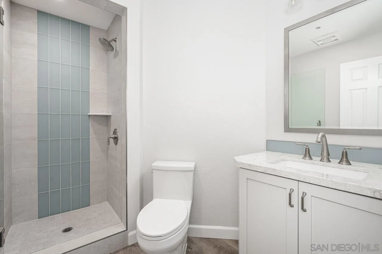4310 Nabal Drive La Mesa, CA 91941 - Photo 12 of 20 a bathroom with a granite countertop toilet a sink a mirror and shower