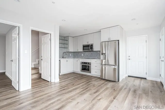 a kitchen with a refrigerator a stove top oven and wooden floor