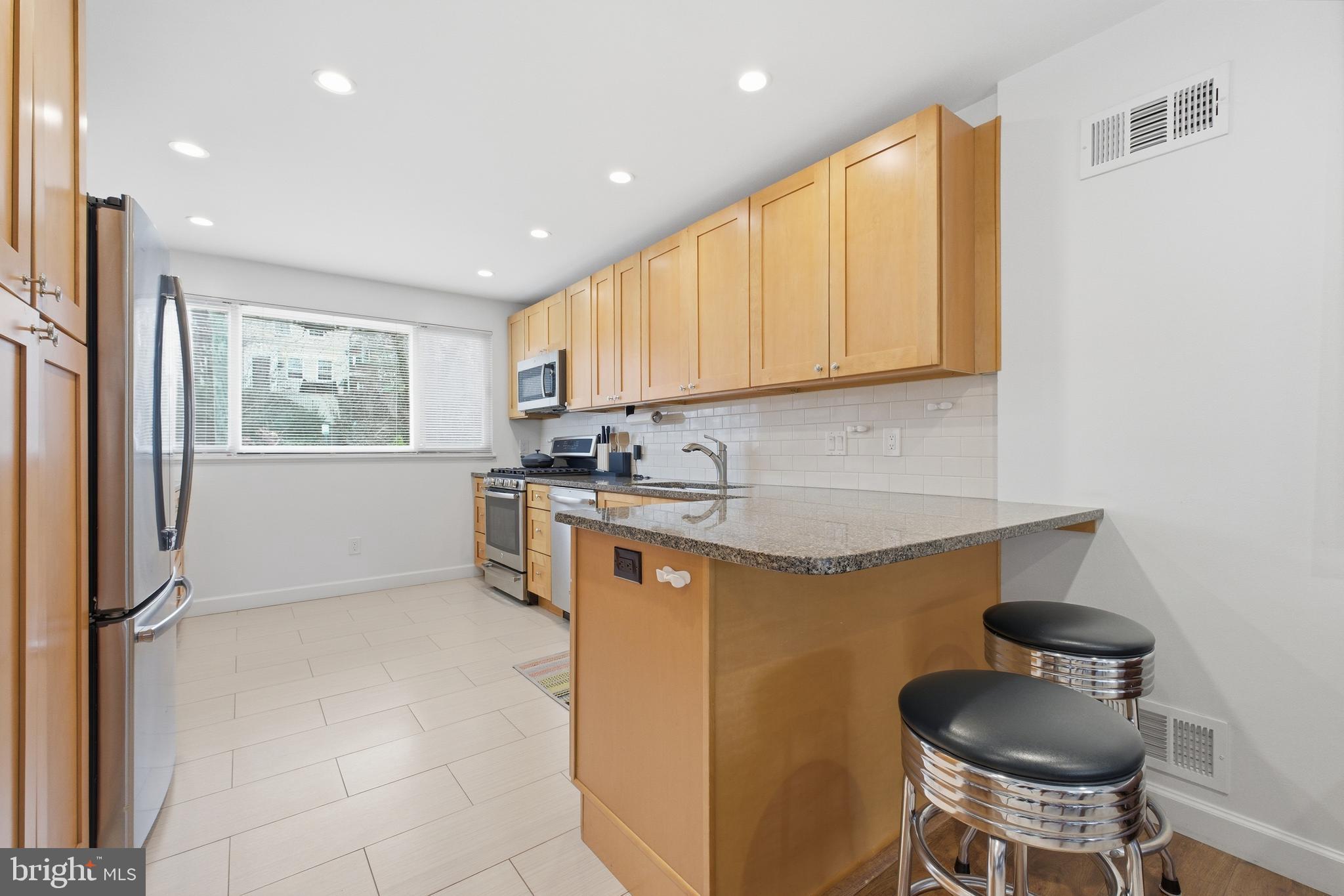 4848 Reservoir Road Northwest Washington, DC 20007 - Photo 11 of 49 a kitchen with stainless steel appliances granite countertop a stove a sink and a refrigerator