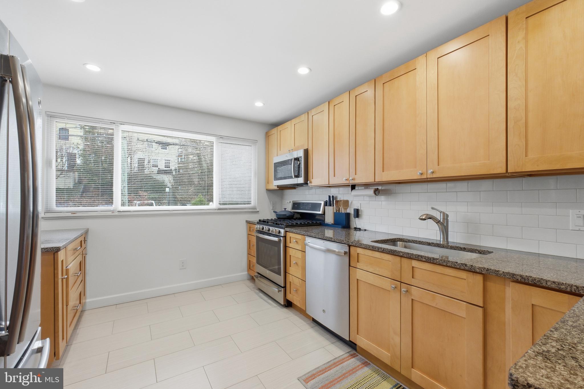 4848 Reservoir Road Northwest Washington, DC 20007 - Photo 13 of 49 a kitchen with stainless steel appliances granite countertop a stove a sink and a microwave
