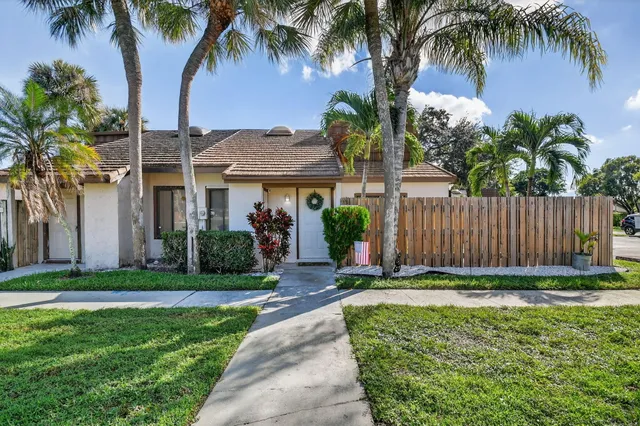front view of a house with a yard and palm trees