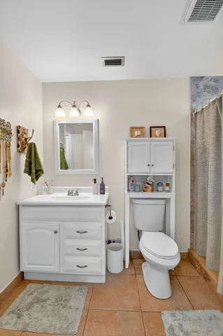 a bathroom with a granite countertop toilet sink and mirror