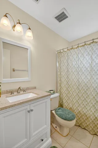 a bathroom with a granite countertop toilet sink mirror and shower