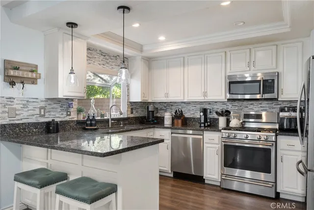 a kitchen with stainless steel appliances kitchen island granite countertop a sink a stove a microwave a counter space and cabinets