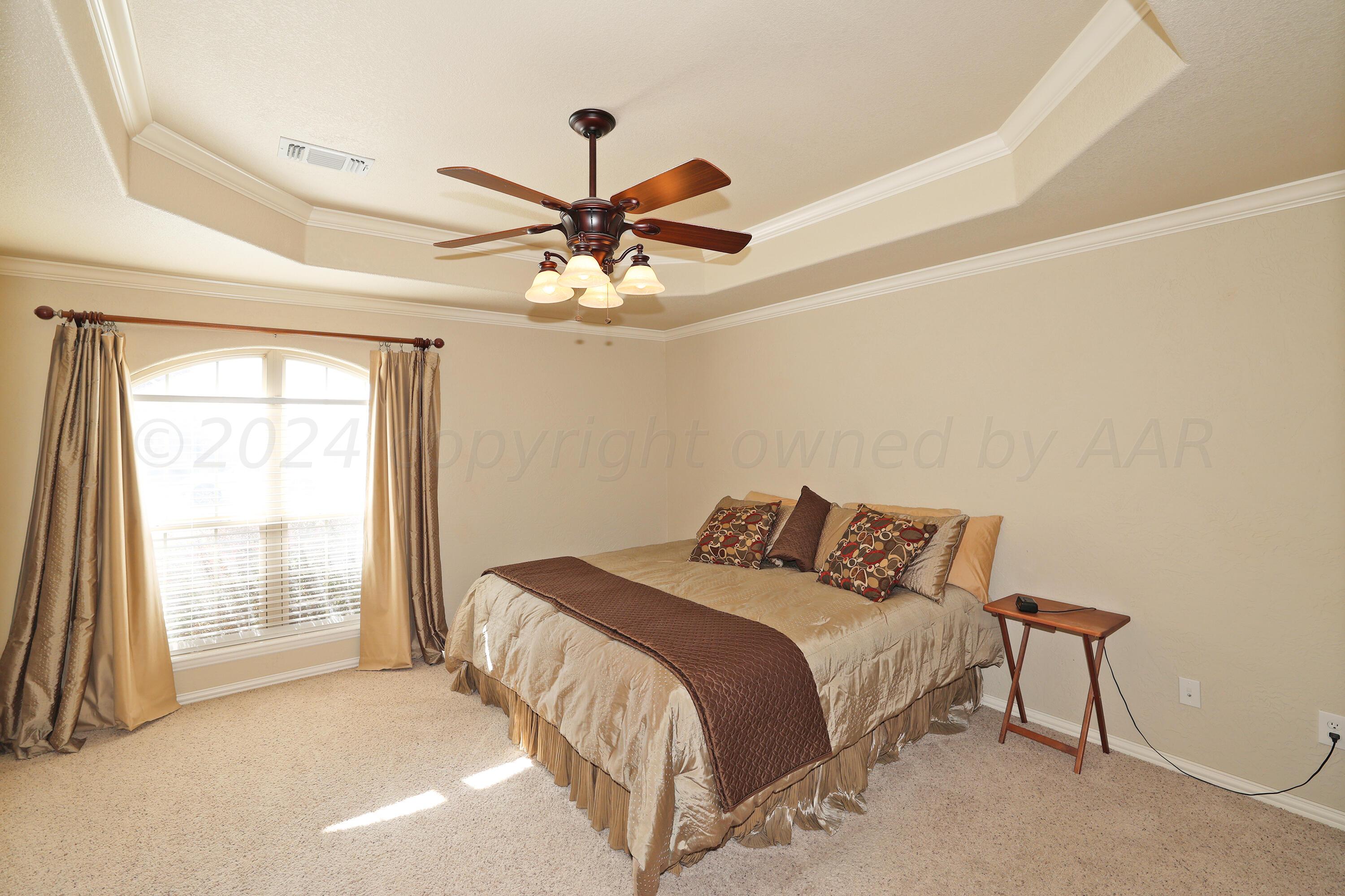 6902 Thunder Road Amarillo, TX 79119 - Photo 11 of 32 a bedroom with a bed and a chandelier