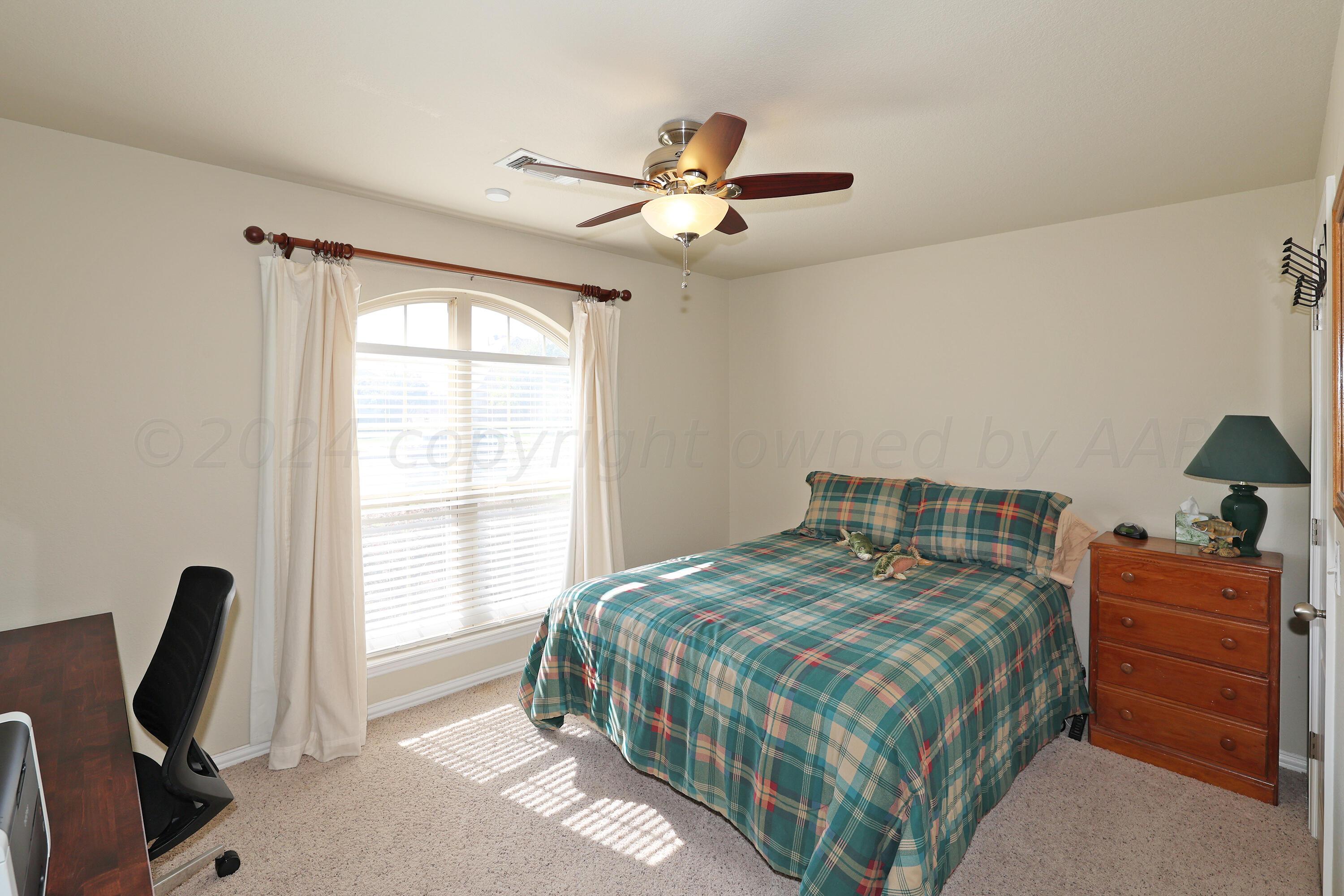 6902 Thunder Road Amarillo, TX 79119 - Photo 17 of 32 a bedroom with a bed a chandelier and a window