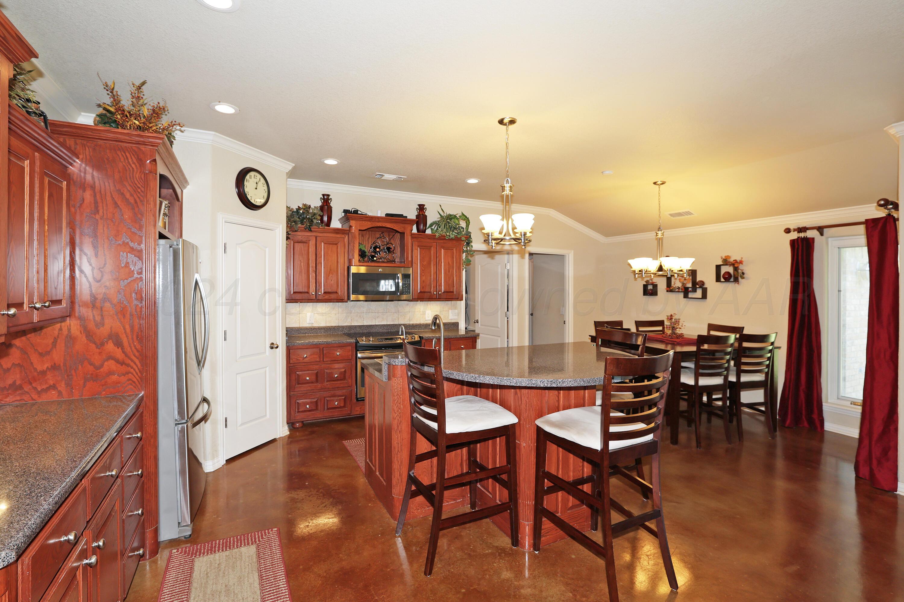 6902 Thunder Road Amarillo, TX 79119 - Photo 8 of 32 a dinning area with stainless steel appliances kitchen island granite countertop furniture and wooden floor