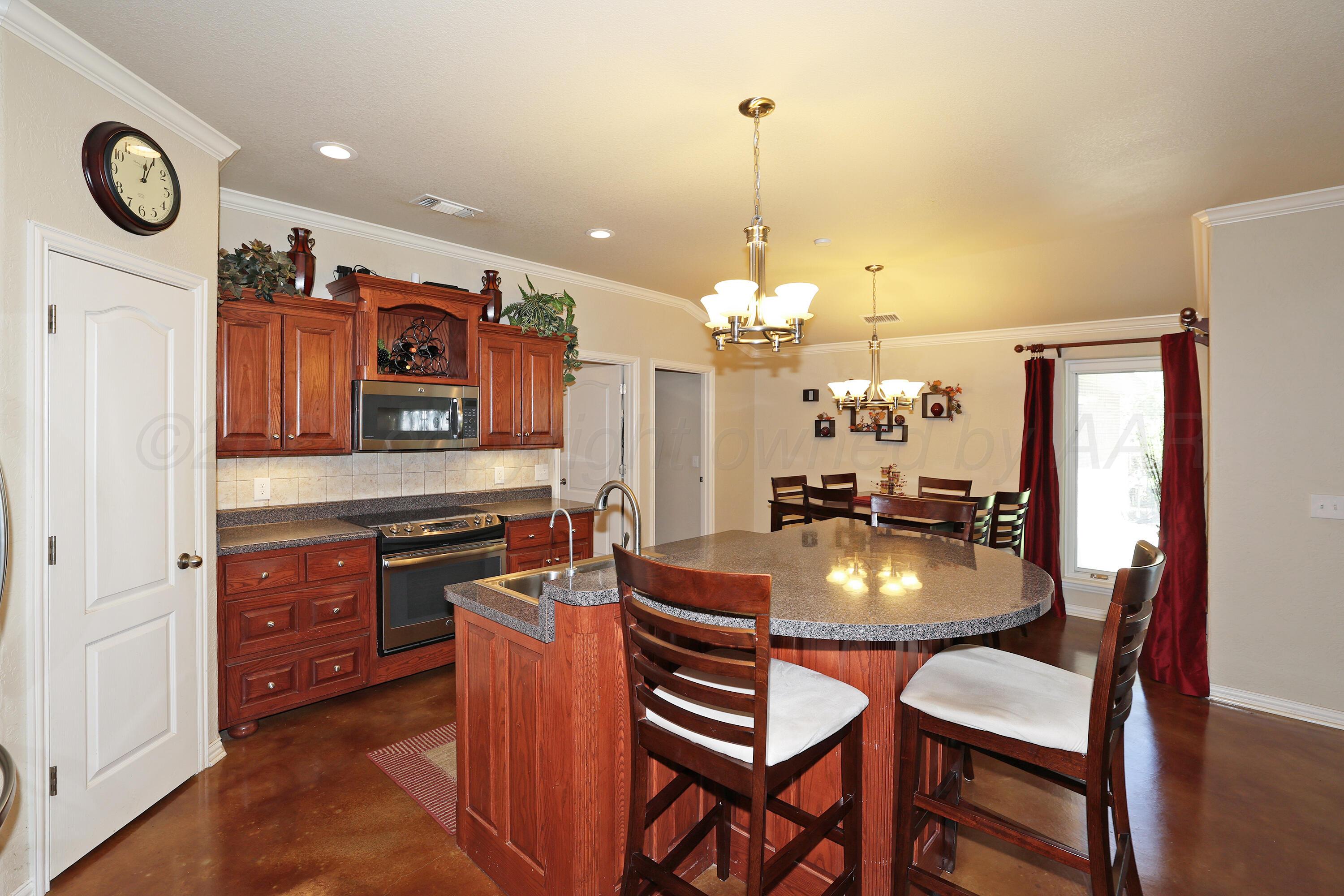 6902 Thunder Road Amarillo, TX 79119 - Photo 9 of 32 a kitchen with stainless steel appliances granite countertop a stove top oven a dining table and chairs with wooden floor