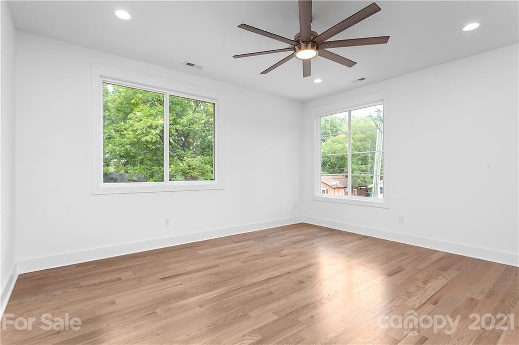 3909 Plainview Road Charlotte, NC 28208 - Photo 16 of 24 an empty room with wooden floor ceiling fan and windows