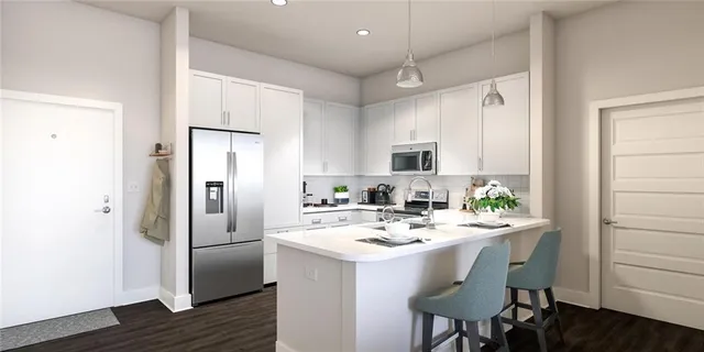 a kitchen with a sink a refrigerator and white cabinets with wooden floor
