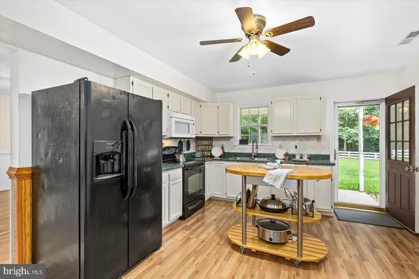 a kitchen with stainless steel appliances granite countertop a refrigerator a stove a sink a dining table and chairs with wooden floor