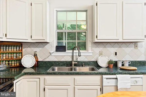 a kitchen with granite countertop a stove a sink and a white cabinets