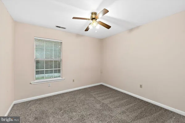 an empty room with a window and a ceiling fan