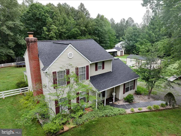 a aerial view of a house in front of a yard with plants and large trees