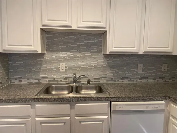 a kitchen with granite countertop a stove sink and cabinets