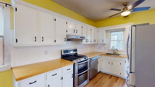 a kitchen with stainless steel appliances white cabinets and a wooden floor