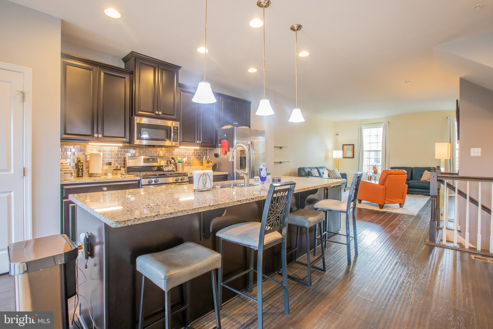 2608 Fiat Drive Hanover, MD 21076 - Photo 14 of 39 a kitchen with a dining table chairs cabinets wooden floor and appliances