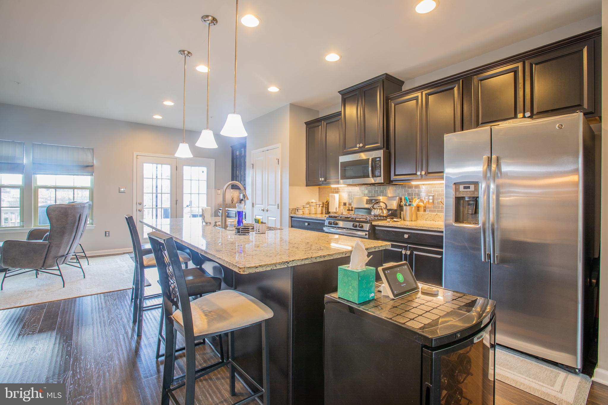 2608 Fiat Drive Hanover, MD 21076 - Photo 16 of 39 a kitchen with stainless steel appliances kitchen island granite countertop a refrigerator a stove a sink a dining table and chairs with wooden floor