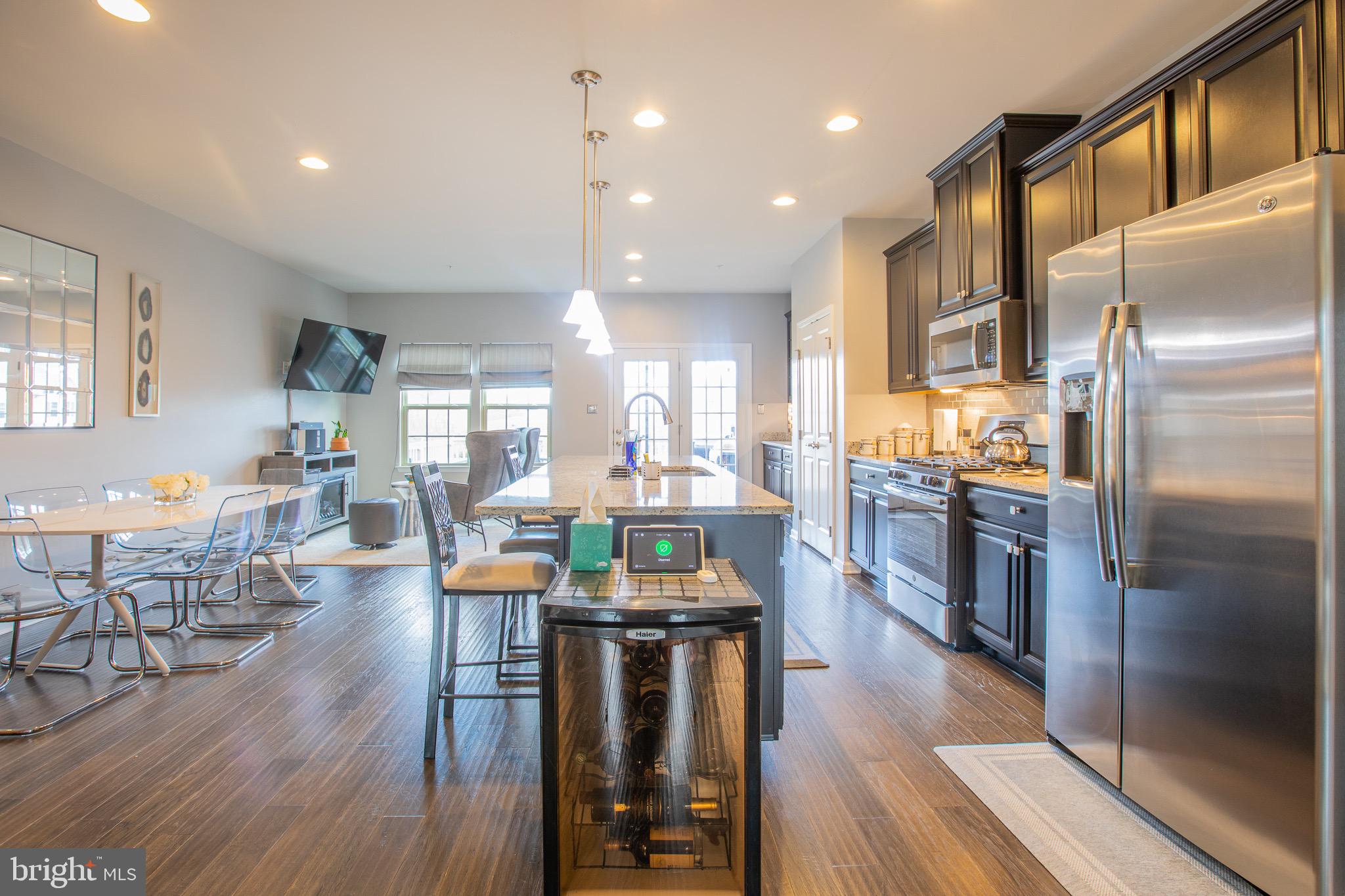 2608 Fiat Drive Hanover, MD 21076 - Photo 17 of 39 a kitchen with stainless steel appliances kitchen island granite countertop a refrigerator a stove a sink a dining table and chairs with wooden floor