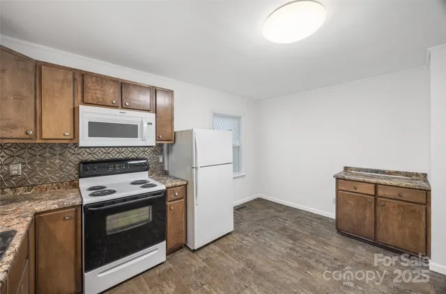 a kitchen with granite countertop a stove top oven and cabinets