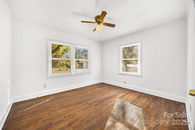an empty room with window and ceiling fan