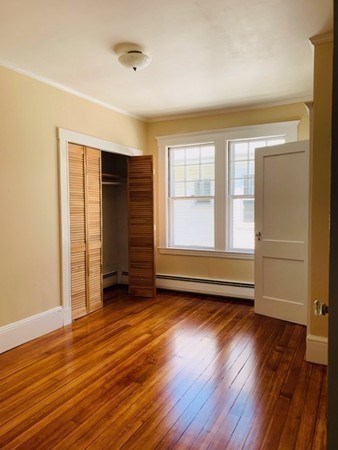 52 Powder House Boulevard, Unit 1 Somerville, MA 02144 - Photo 10 of 30 an empty room with wooden floor and windows