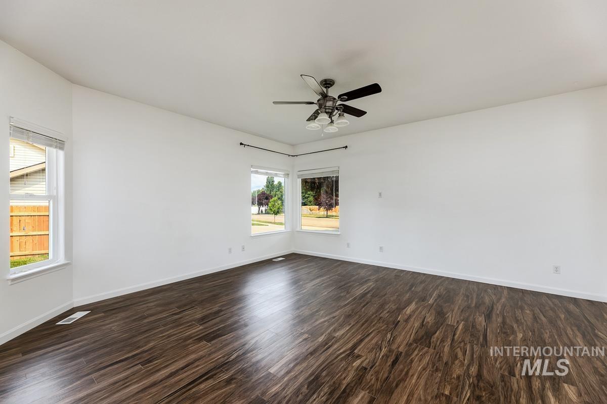 2575 S Bayou Meridian, ID 83642 - Photo 12 of 30 Bright interior with wood-finish flooring, white walls, multiple windows, and a ceiling fan with integrated lighting