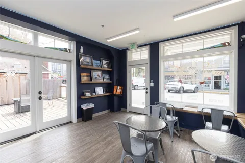 a living room with furniture hard wood floor and a floor to ceiling window